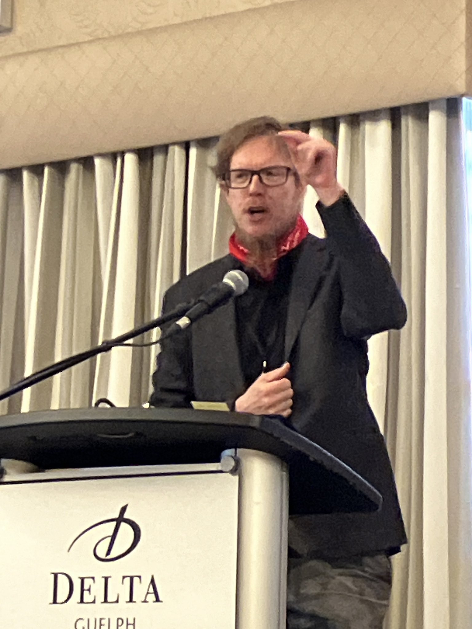 Jesse Hirsh speaking at a Delta hotel podium.