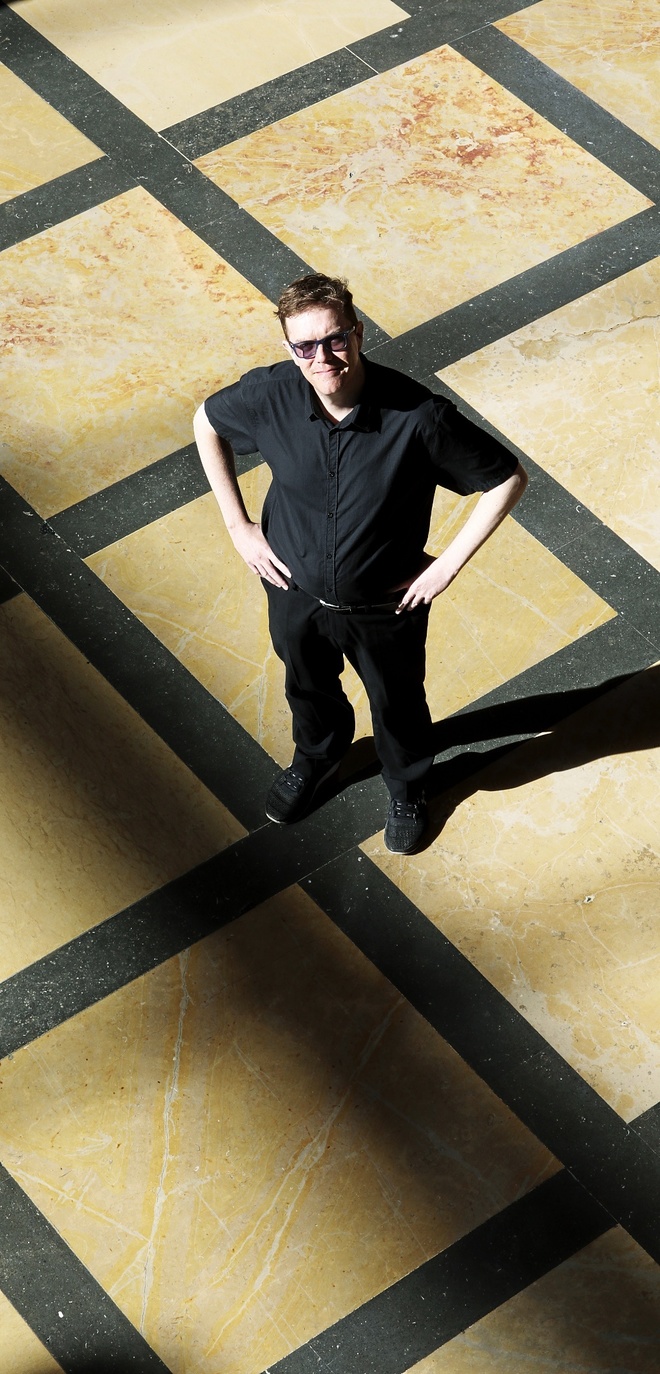 Jesse Hirsh standing on a tiled floor in strong sunlight, viewed from above.