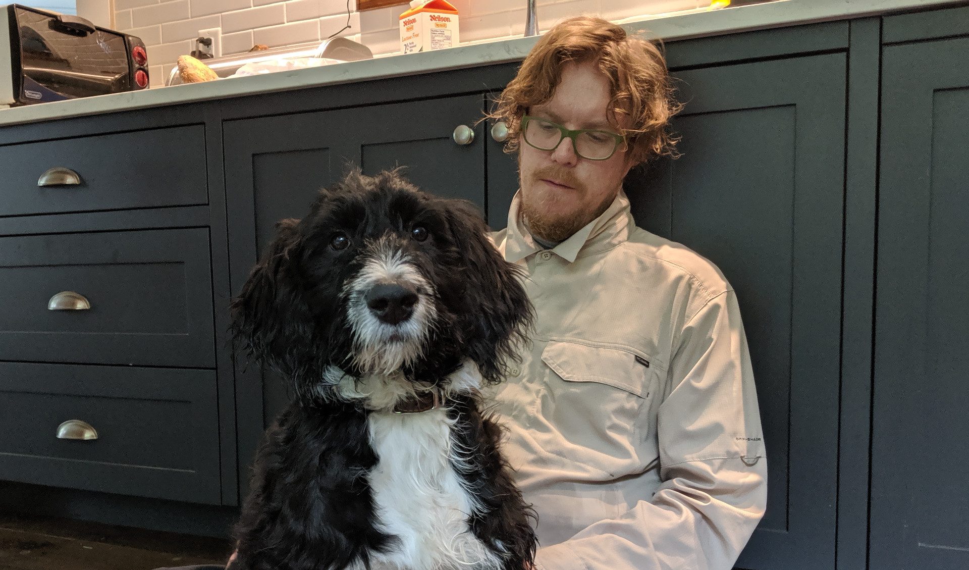 Jesse Hirsh speaking into a handheld microphone onstage with his name projected behind him.